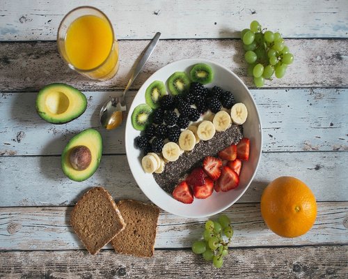 Fresh salad bowl with avocado and greens on a wooden table