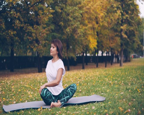 Woman doing yoga stretches in a peaceful park setting at sunset